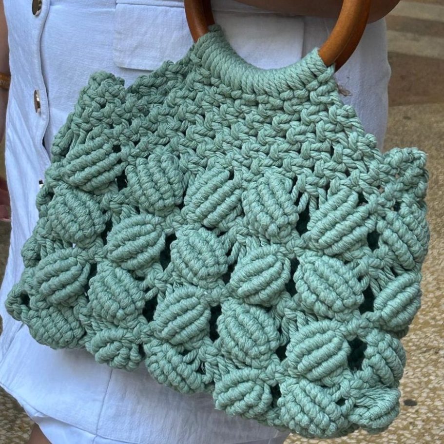 Sac en macramé vert menthe avec anses en bois, motif texturé en relief.