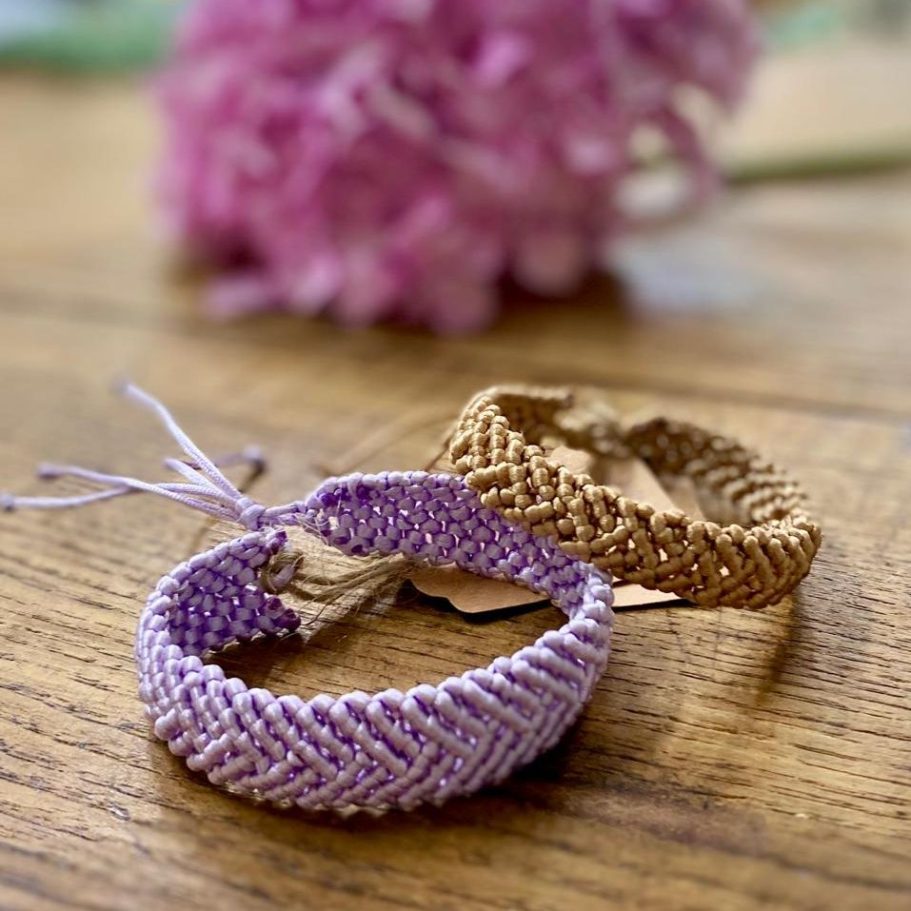 Bracelets en macramé, l'un violet et l'autre marron, posés sur une surface en bois.