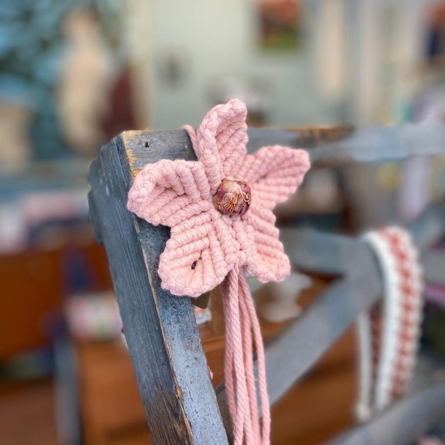 Fleur en coton rose tissée en macramé sur une chaise en bois.