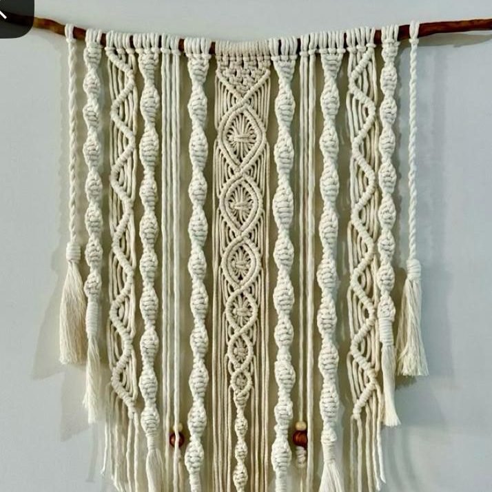 Tissage mural en macramé avec des motifs en corde blanche et des franges.